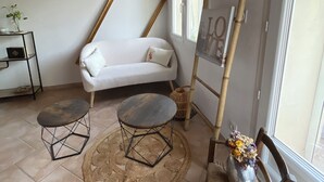 A cozy room with a white sofa, two round tables, a wooden chair, and a ladder leaning against the wall. - Apartment near the sea and Montpellier (Pignan)