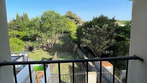 A balcony with a view of a garden, outdoor furniture, and a clear blue sky. - Apartment near the sea and Montpellier (Pignan)