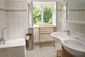 Ein Badezimmer mit Badewanne, Waschbecken, Fenster und Handtuchhalter.