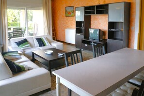 Een woonkamer met een bank, een eettafel en een televisie.