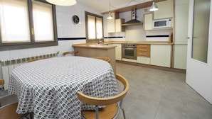 Una cocina compacta con una mesa de comedor, sillas, microondas y estufa.