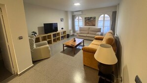 Una sala de estar con televisor, sofá y lámpara.