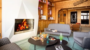 A cozy room with a fireplace, a sofa, a dining table with breakfast items, and a bookshelf. - Mountain-ready Apartment for 6 (La Plagne-Tarentaise)