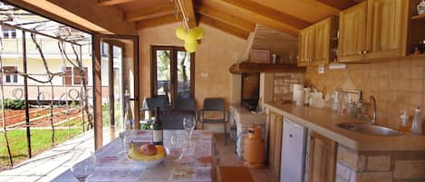 A kitchen with stone countertops, wooden cabinets, and a dining area with a table set for two.