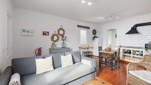Una sala de estar con un sofá gris, una mesa de centro de madera y un comedor con una mesa y sillas de madera.