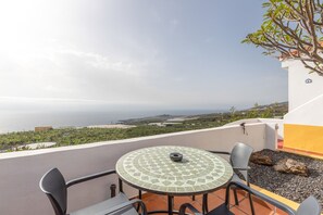 A terrace with a round table and chairs, overlooking a coastal landscape. - Vacation Home with Sea Views (Breña Baja)
