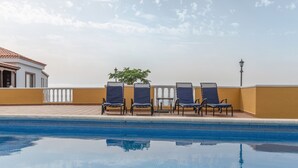 Una piscina con sillas de descanso y un farol.
