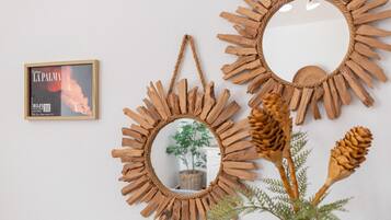 Three rustic wooden mirrors with a sunburst design, a framed picture, and a potted plant with pine cones.