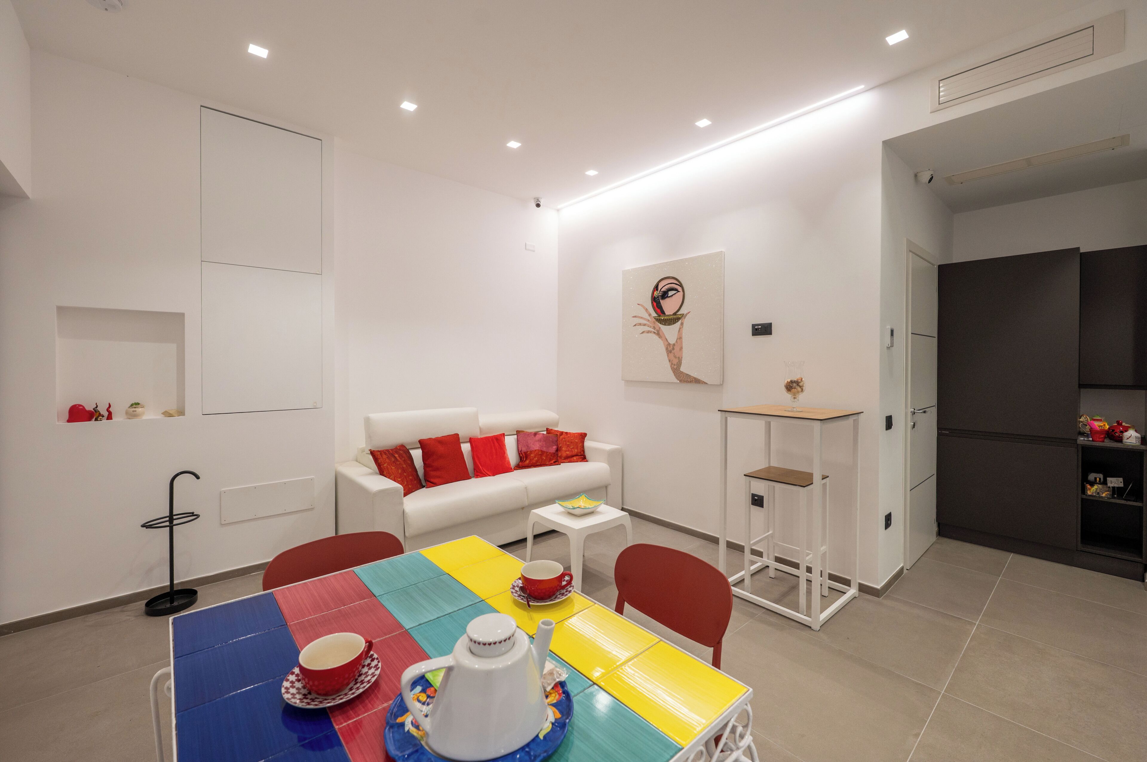 Une pièce moderne et bien éclairée, comprenant une table à manger, des chaises, un canapé et un réfrigérateur.