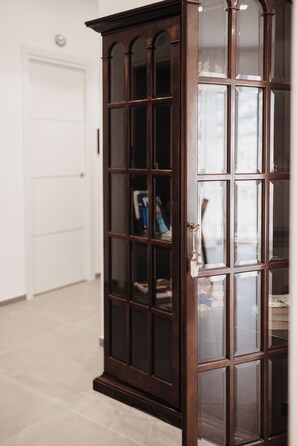 A dark wooden cabinet with glass doors, a white door in the background, and a tiled floor. - B&B Zerottonove (Salerno)
