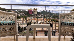 A balcony with wicker chairs and a table, overlooking a cityscape with buildings and hills. - B&B Zerottonove (Salerno)