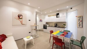 A modern kitchen with white cabinets, a dining table with colorful placemats, and a small side table. - B&B Zerottonove (Salerno)