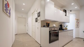 A modern kitchen with white cabinetry, an oven, and a countertop with a kettle and flowers. - B&B Zerottonove (Salerno)