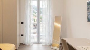 A hotel room with a bed, a desk, a chair, a mirror, and a view through a door. - B&B Zerottonove (Salerno)