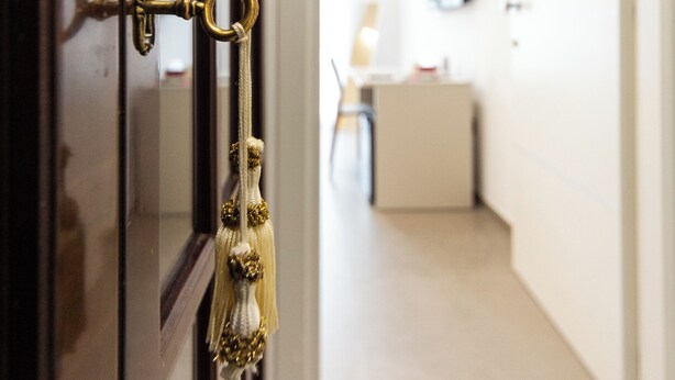 A brass door handle with a tassel hanging from it, leading into a hallway with a desk and chair. - B&B Zerottonove (Salerno)