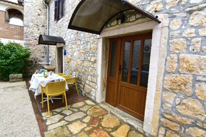 A stone building with a wooden door and a covered outdoor seating area. - Lovely ground-floor flat with shared pool in Tar (Tar)