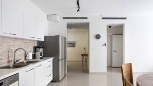 A modern kitchen with white cabinets, a stainless steel refrigerator, and a coffee maker.