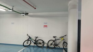 A parking garage with two bicycles parked against the wall, a white pillar, and a blue floor.