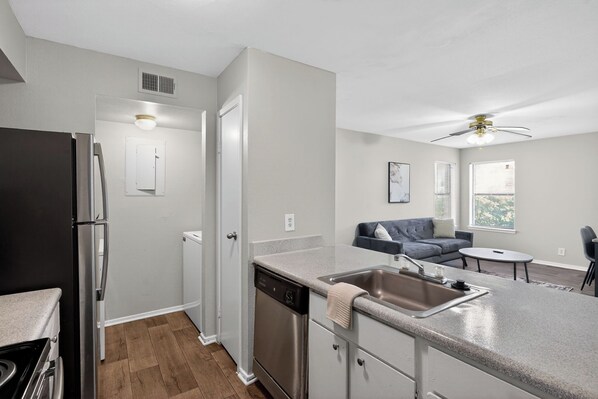 A modern kitchen with a dishwasher, a refrigerator, and a dining area with a table and chairs.