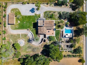 Vista aérea de una propiedad residencial con piscina, entrada de carril curva y jardín ajardinado.