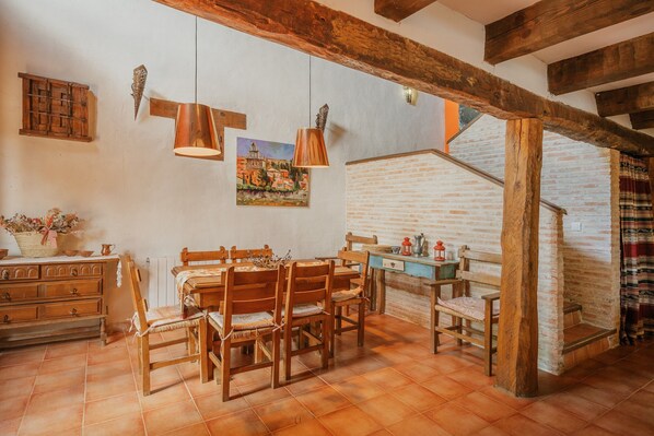 A rustic dining area with wooden furniture, a brick wall, and exposed wooden beams.