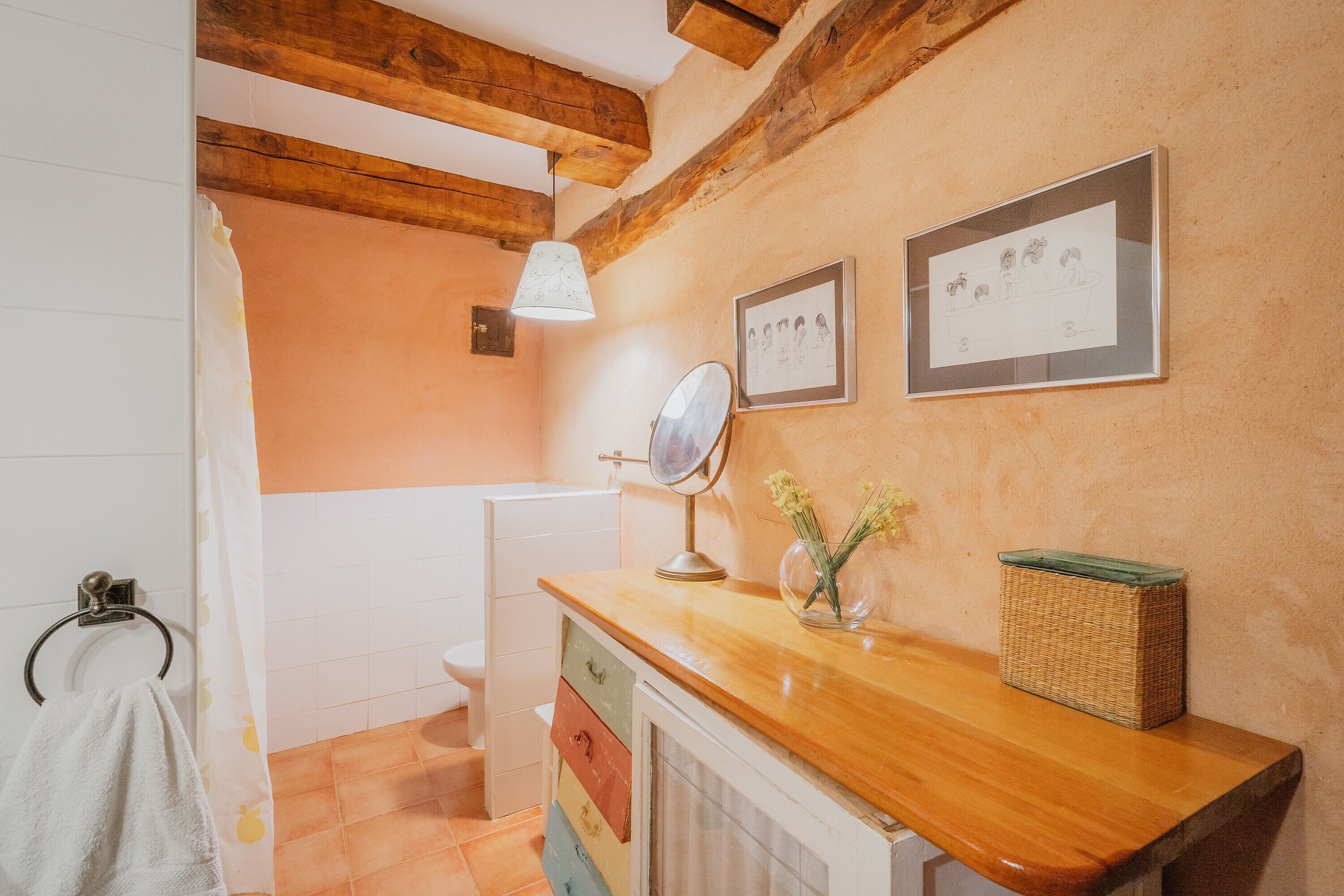 Ein Badezimmer mit Holzboden, einer weißen Toilette, einem Holzwaschtisch mit Spiegel und einem gerahmten Bild an der Wand.