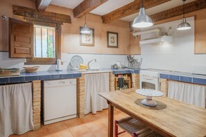 A kitchen with a wooden table, a dishwasher, and a stove.