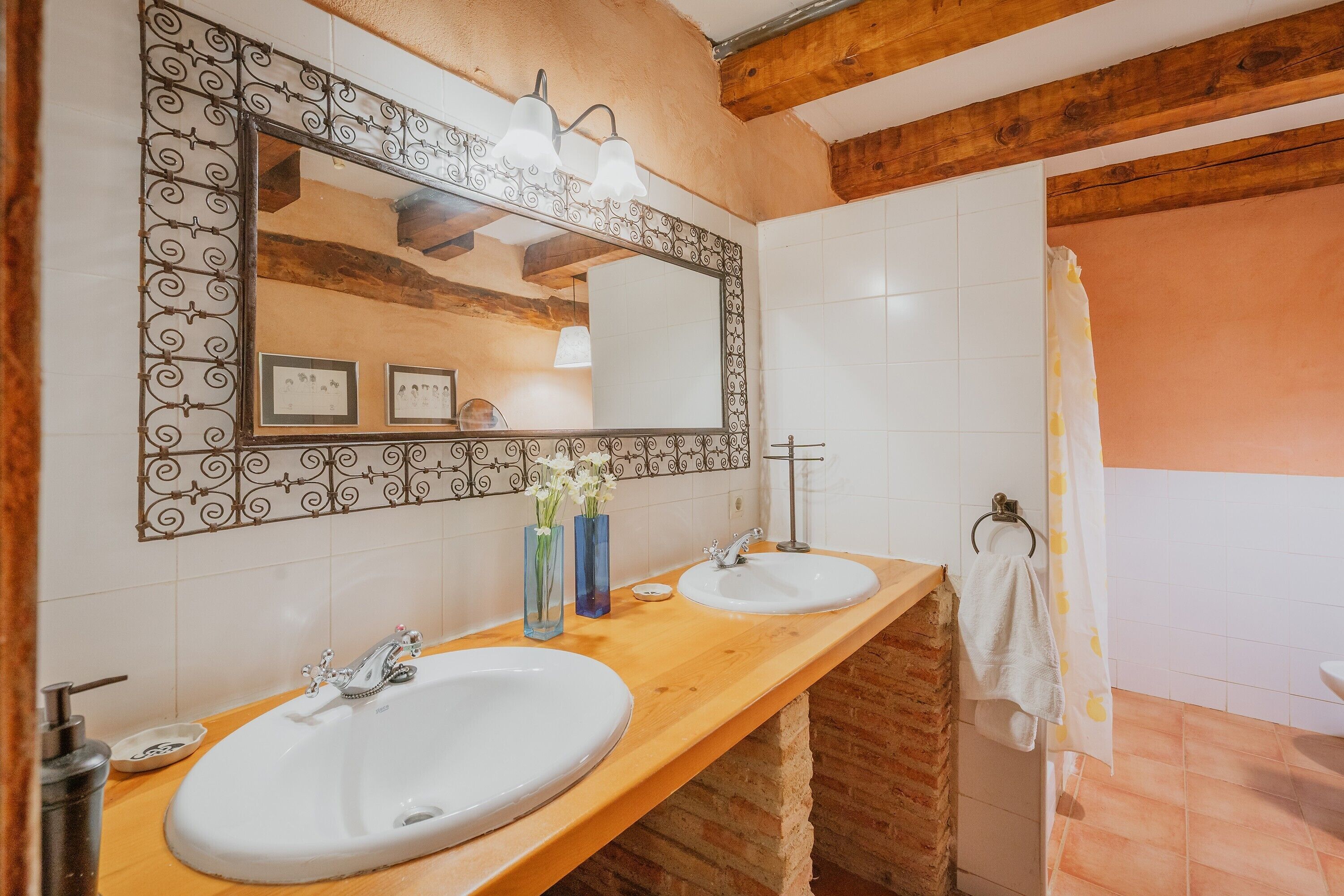 Een badkamer met twee wasbakken, een spiegel met decoratieve lijst en een douchegordijn.