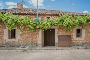 A rustic building with a tiled roof, a wooden door, and a window with a barred shutter.