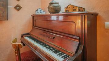 Un piano à queue avec un placage en bois, un fauteuil rouge rembourré et de petites maisons miniatures posées sur le dessus.