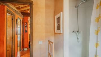 A hallway with wooden doors, a shower with a showerhead, and a tiled wall.