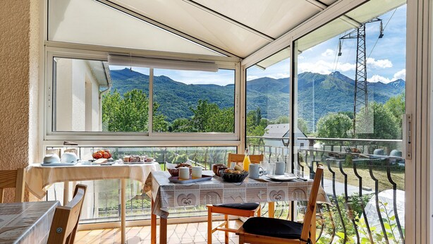 A dining area with a table set for breakfast, a view of mountains, and a glass door.