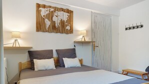 Une chambre à coucher avec un lit, deux lampes de chevet, une carte du monde accrochée au mur, une tête de lit en bois et un porte-manteau.