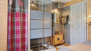 Een moderne badkamer met een douchecabine van glas, een houten kastje en een spiegel.