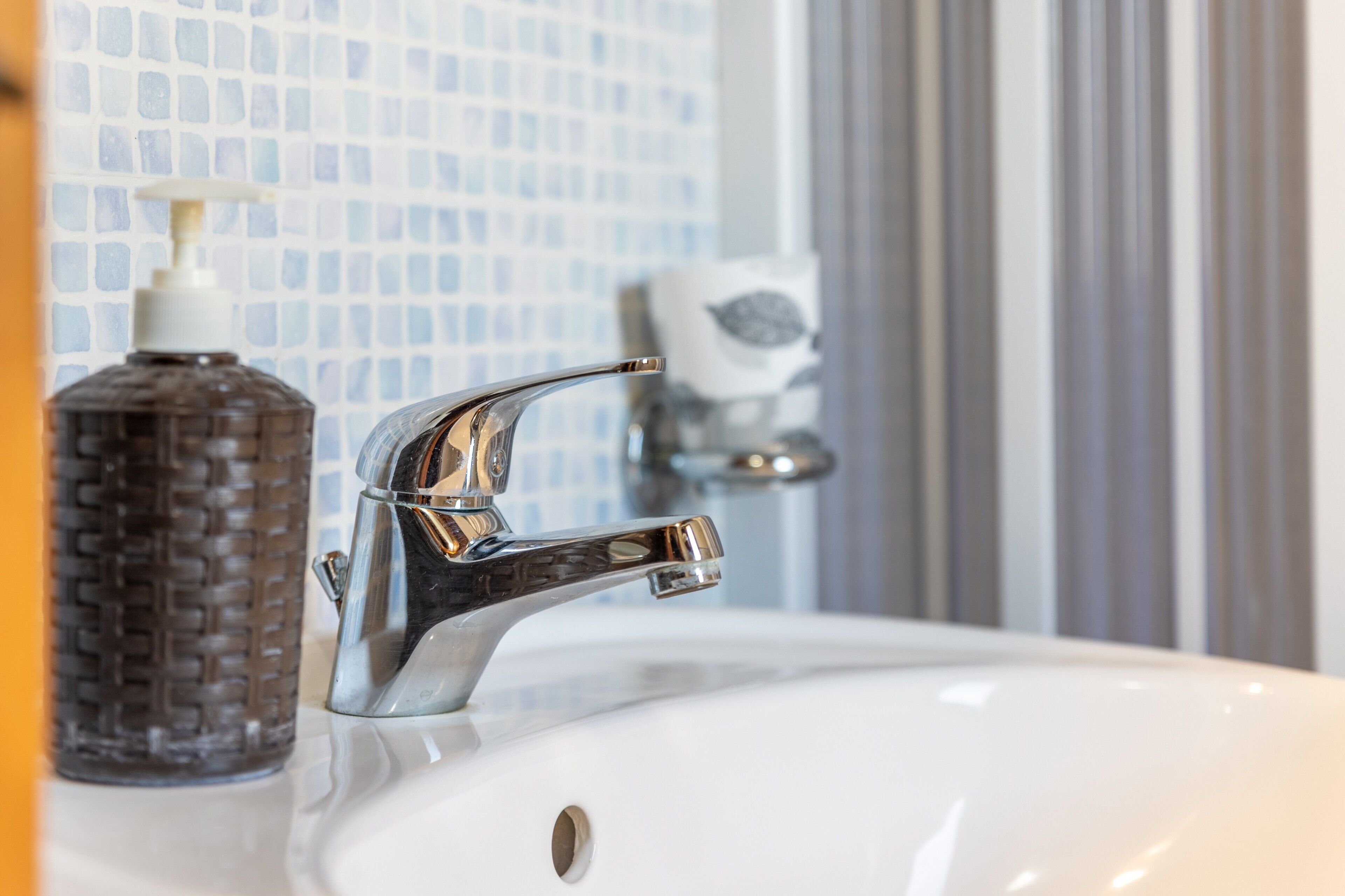 Un lavabo de salle de bain avec un robinet chromé, un distributeur de savon et un porte-savon.