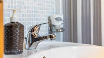 Un lavabo de salle de bain avec un robinet chromé, un distributeur de savon et un porte-savon.