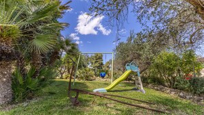 A playground with a slide and swings, surrounded by greenery and trees. - Apartment 'Alfa' with Shared Terrace, Wi-Fi and Air Conditioning (Punta Secca)