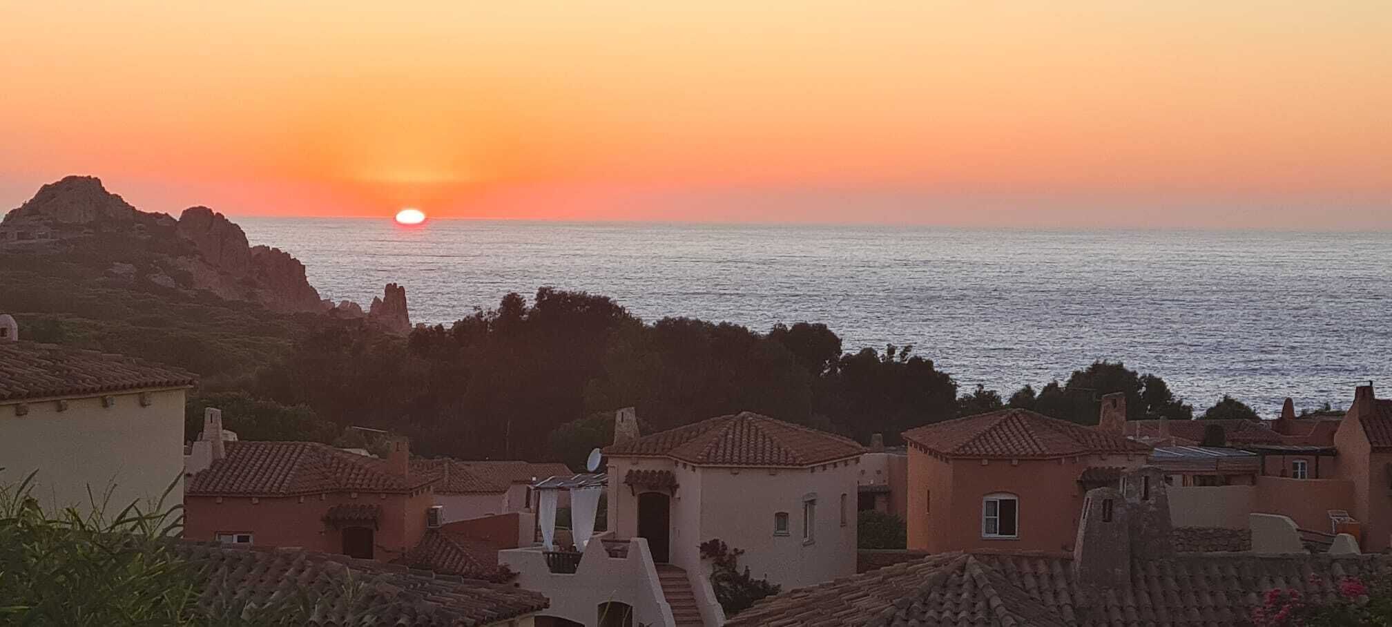 Ein Küstendorf mit traditioneller Architektur, einem Sonnenuntergang und dem Meer.