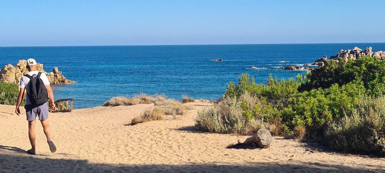 A sandy beach with a clear view of the ocean and rocky formations.