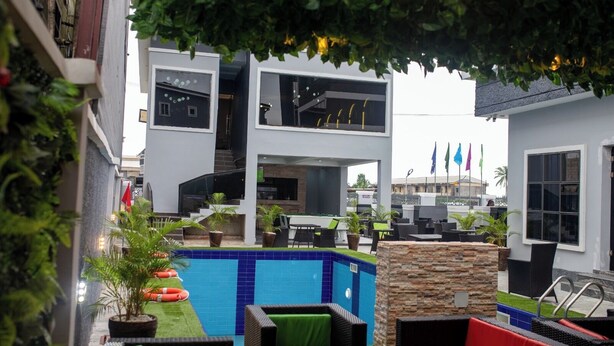 A modern building with a swimming pool, outdoor seating, and flags.