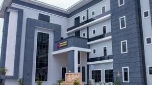 A multi-story hotel with a modern architectural design, featuring a prominent entrance with a glass facade and a sign indicating it is a hotel.