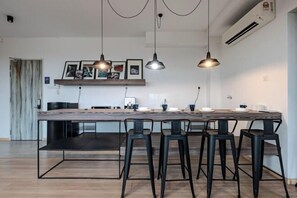 A modern kitchen with a wooden island, bar stools, pendant lighting, and framed artwork on the wall.