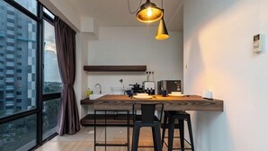 Una cocina moderna con encimera de madera, taburetes negros y una lámpara colgante.