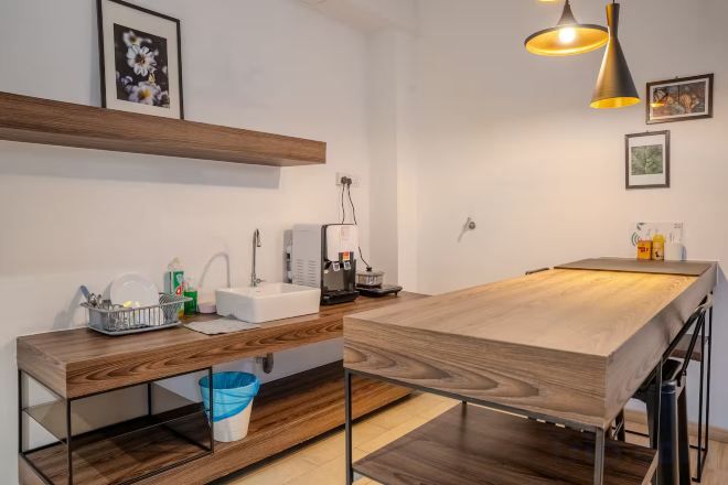Cozinha moderna com bancada de madeira, pia e luminária pendente.