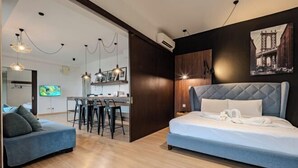 Una habitación de hotel moderna con cama, sofá, zona de comedor y cocina.