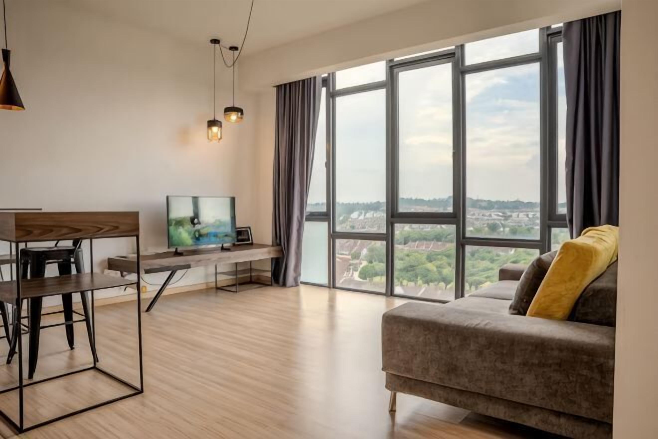 A modern living room with a sofa, a dining table, a TV, and large windows offering a city view.