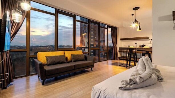 Una habitación moderna con un ventanal grande, un sofá, una cama y una zona de cocina.