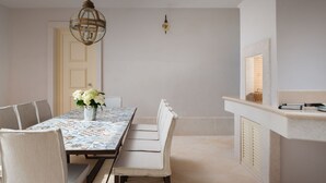 En matplats med ett långt bord, stolar, en vas med blommor, en hängande lampa och en öppen spis.