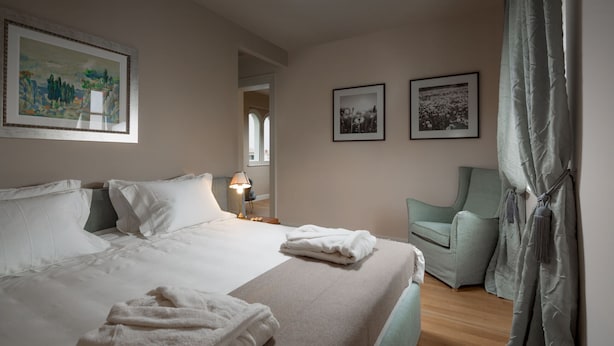 Ein Hotelzimmer mit einem großen Bett, einem Sessel, einem Schreibtisch und einem Fenster.