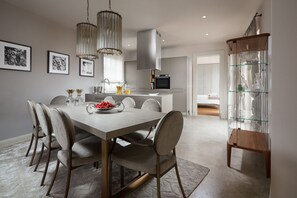 Uma cozinha moderna com uma mesa de jantar, cadeiras, luminárias pendentes e um aparador de vidro.